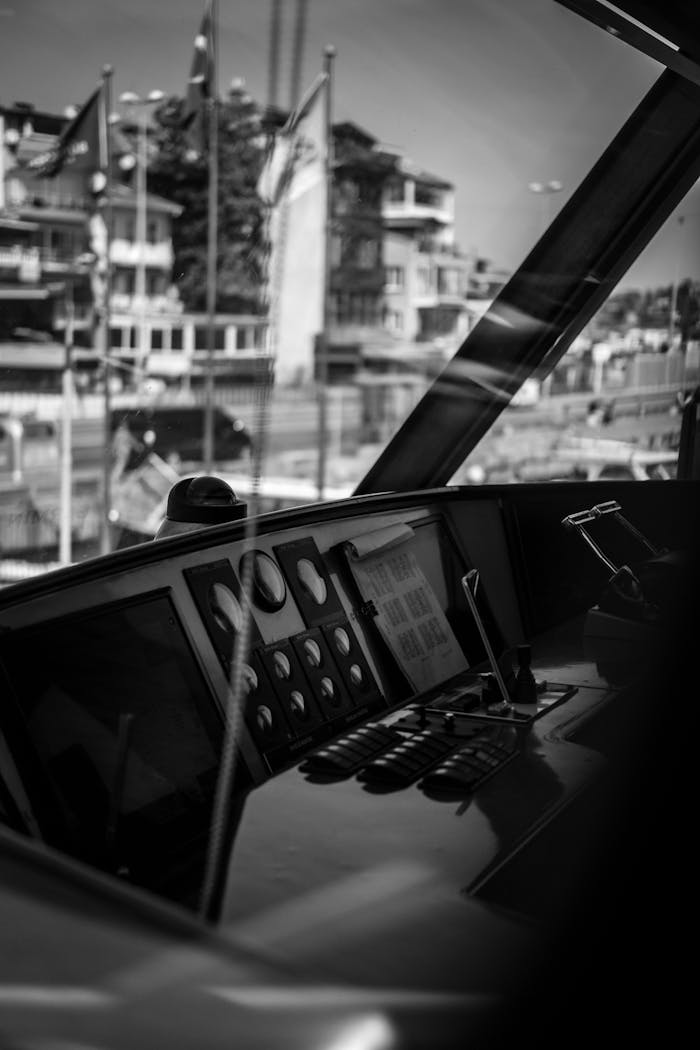 Close-up of a yacht cockpit with cityscape in the background, in black and white.