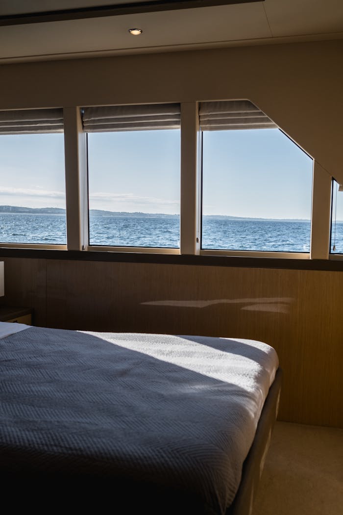 Elegant yacht bedroom interior with stunning ocean view through large windows.
